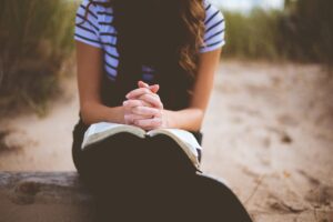 young girl with open Bible & prayer hands